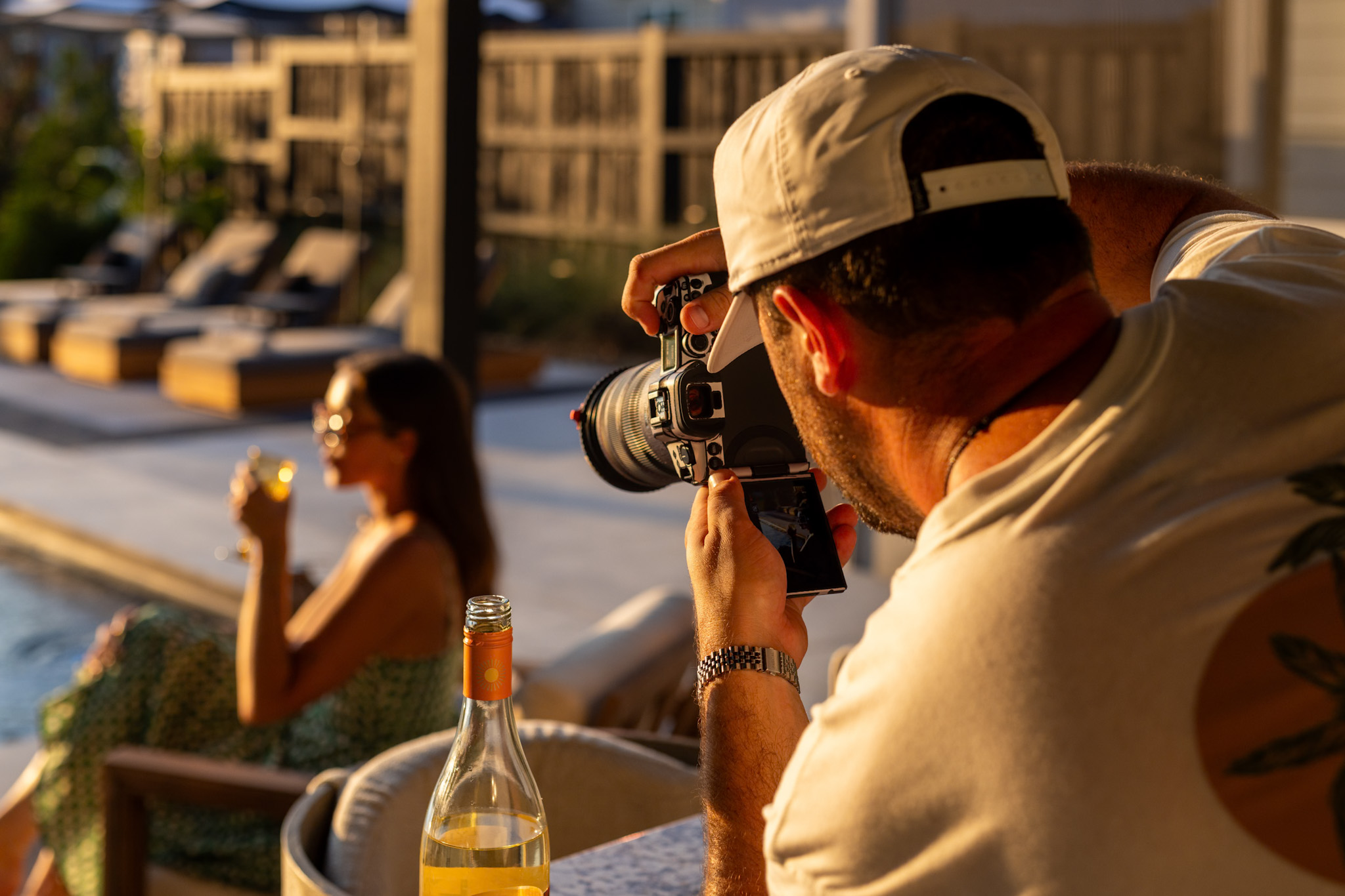 Photographer capturing a golden-hour lifestyle scene by a pool — the craft in action